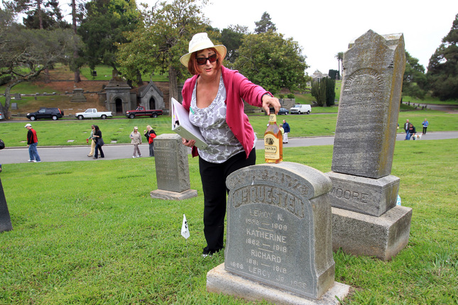 Barbara Gibson places a bottle of Yukon Jack’s namesake hooch at the tomb of Leroy Napoleon “Jack” McQuesten.