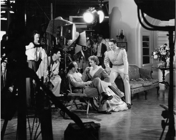 Michael Curitz (seated), Olivia de Havilland, Errol Flynn on the set. CHARGE.png